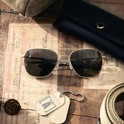 Randolph Engineering Aviator sunglasses on a wooden surface with a bag, rope, and dog tags.