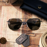Class A Aviator - Military Olive & American Gray Aviator Sunglasses and dog tags on a wooden surface with a vintage document
