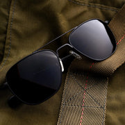 Black Randolph aviator sunglasses on a textured brown flight bag